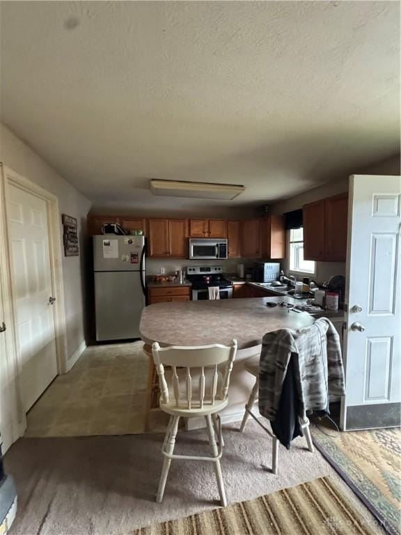 428 E Center St, Germantown, OH 45327 - kitchen featuring appliances with stainless steel finishes, a textured ceiling, a breakfast bar, and brown cabinetry