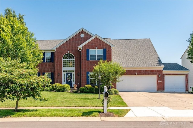 24 Dinsley Pl, Springboro, OH 45066 - view of front of property with a front yard, concrete driveway, a garage, brick siding, and a shingled roof