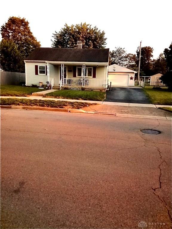 34 William St, West Carrollton, OH 45449 - single story home with covered porch, an outbuilding, a chimney, asphalt driveway, and a detached garage