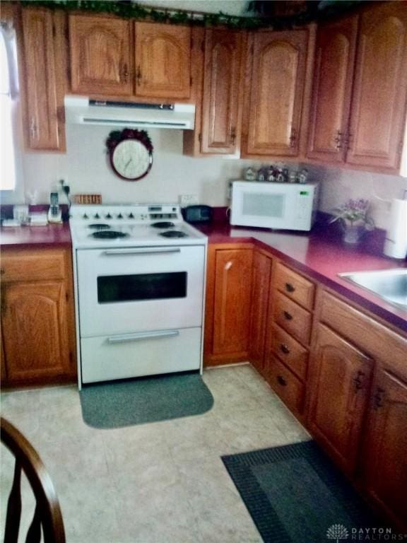 34 William St, West Carrollton, OH 45449 - kitchen featuring white appliances, under cabinet range hood, and brown cabinetry