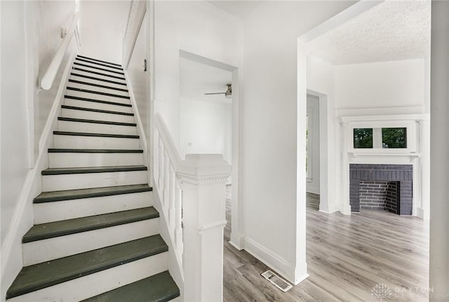 36 Leaman St, Xenia, OH 45385 - stairway with a brick fireplace, wood finished floors, and a ceiling fan