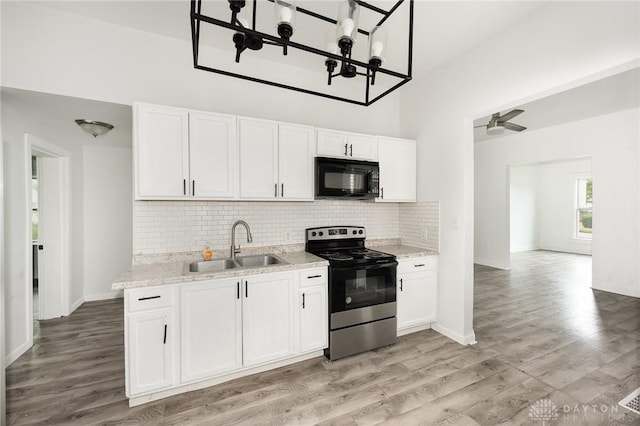36 Leaman St, Xenia, OH 45385 - kitchen with black microwave, electric stove, white cabinets, decorative backsplash, and a towering ceiling