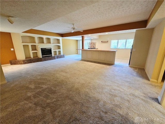 1962 Fountain View Dr, Dayton, OH 45414 - unfurnished living room with light carpet, ceiling fan, a textured ceiling, built in shelves, and a tile fireplace