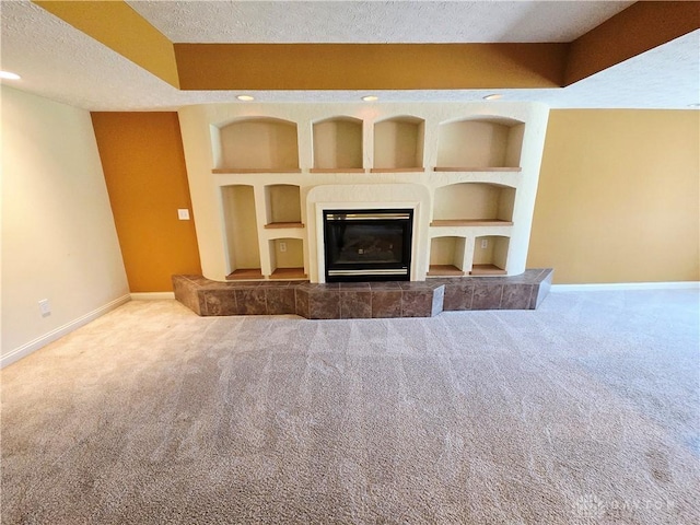 1962 Fountain View Dr, Dayton, OH 45414 - unfurnished living room with carpet flooring, a textured ceiling, built in features, and a tiled fireplace