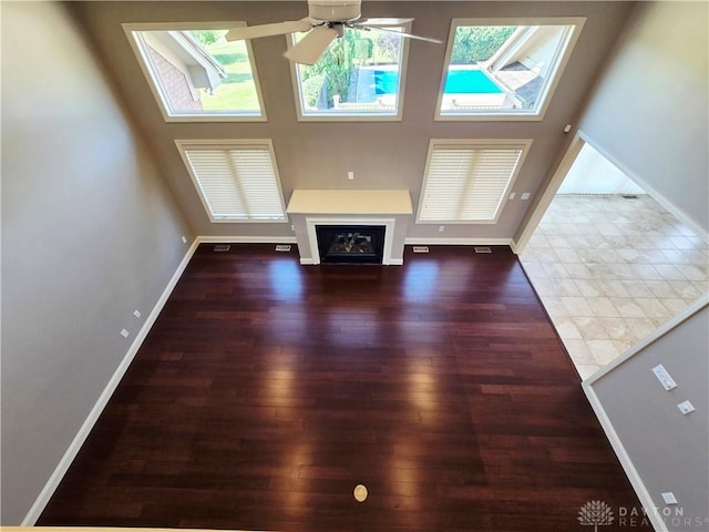 1962 Fountain View Dr, Dayton, OH 45414 - unfurnished living room with plenty of natural light, a ceiling fan, wood finished floors, and a glass covered fireplace
