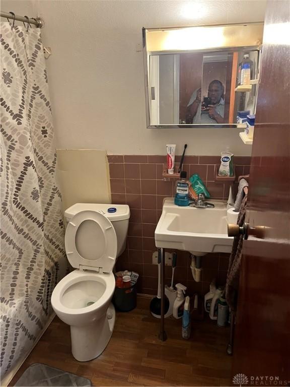4051 Crest Dr, Dayton, OH 45416 - full bath with wood finished floors, a shower with shower curtain, a wainscoted wall, and tile walls