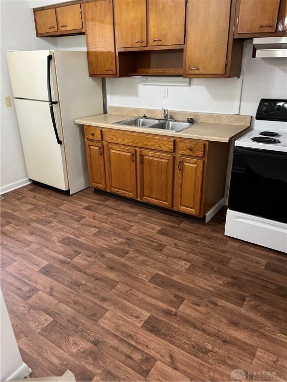 4051 Crest Dr, Dayton, OH 45416 - kitchen featuring white appliances, wall chimney exhaust hood, dark wood-type flooring, and light countertops
