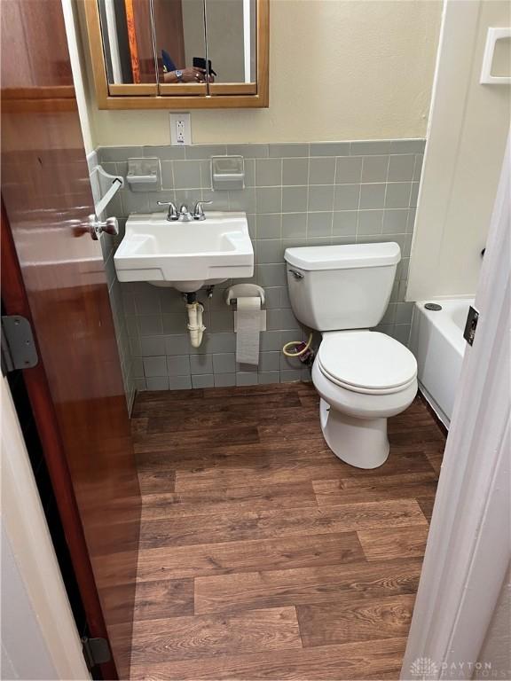 4051 Crest Dr, Dayton, OH 45416 - full bathroom featuring wood finished floors, a tub, a wainscoted wall, and tile walls