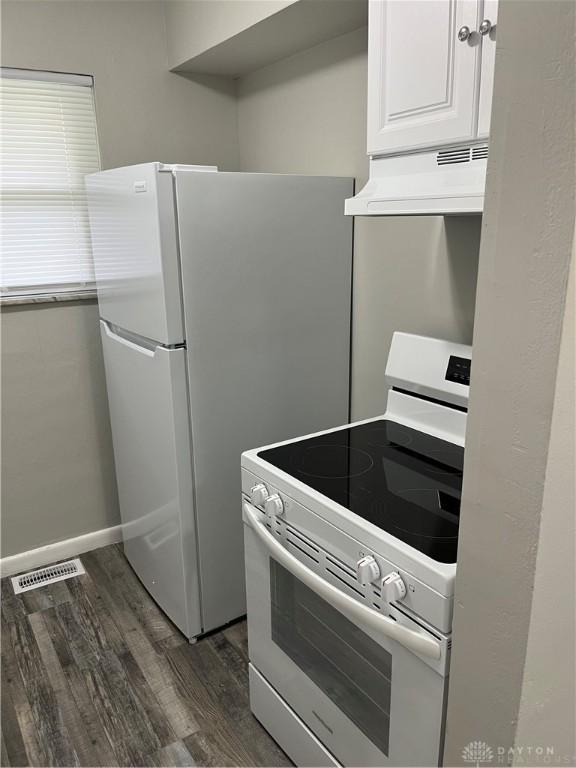 4051 Crest Dr, Dayton, OH 45416 - kitchen with white range with electric cooktop, under cabinet range hood, dark wood-type flooring, and white cabinetry