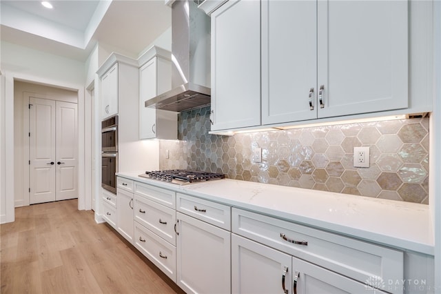 9508 Magnolia Ct, Washington Twp, OH 45458 - kitchen with wall chimney exhaust hood, stainless steel appliances, light wood-style flooring, white cabinets, and decorative backsplash