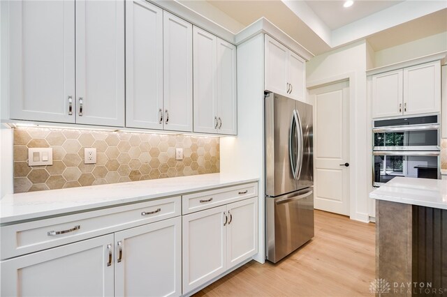 9508 Magnolia Ct, Washington Twp, OH 45458 - kitchen with appliances with stainless steel finishes, light wood finished floors, tasteful backsplash, white cabinetry, and light stone counters