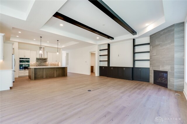 9508 Magnolia Ct, Washington Twp, OH 45458 - unfurnished living room with recessed lighting, a fireplace, a tray ceiling, light wood-style flooring, and beam ceiling