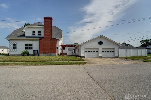 513 S High St, Arcanum, OH 45304 - view of front of house with a chimney, driveway, an attached garage, and roof with shingles