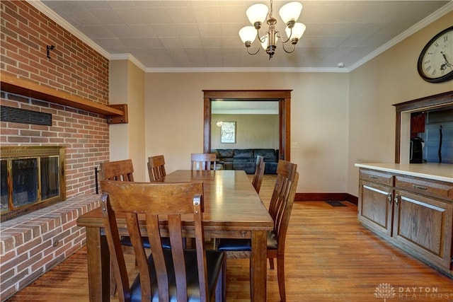 513 S High St, Arcanum, OH 45304 - dining space with a chandelier, wood finished floors, crown molding, and a brick fireplace
