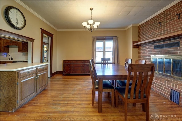 513 S High St, Arcanum, OH 45304 - dining room featuring a chandelier, a brick fireplace, crown molding, and light wood finished floors