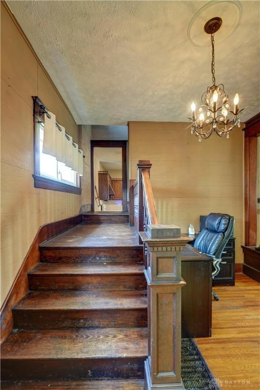 513 S High St, Arcanum, OH 45304 - stairs featuring wood finished floors, a chandelier, and a textured ceiling