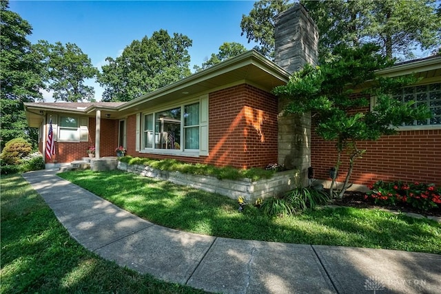 5975 Oakridge Dr, Hamilton, OH 45011 - view of property exterior with a chimney, brick siding, and a yard