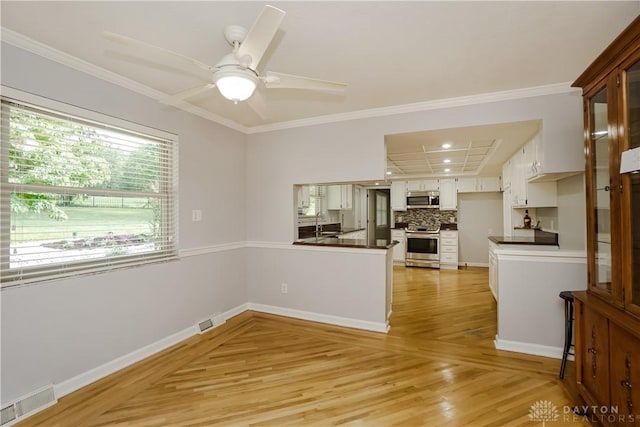 5975 Oakridge Dr, Hamilton, OH 45011 - kitchen featuring appliances with stainless steel finishes, dark countertops, light wood-type flooring, a peninsula, and ornamental molding