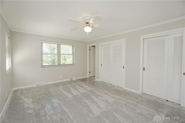 5975 Oakridge Dr, Hamilton, OH 45011 - unfurnished bedroom featuring two closets, ornamental molding, light carpet, and a ceiling fan
