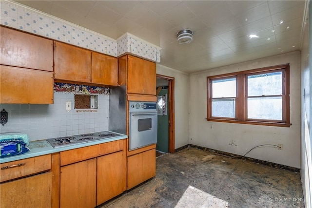 2005 Queen Ave, Middletown, OH 45044 - kitchen featuring oven, stainless steel stovetop, backsplash, light countertops, and brown cabinetry
