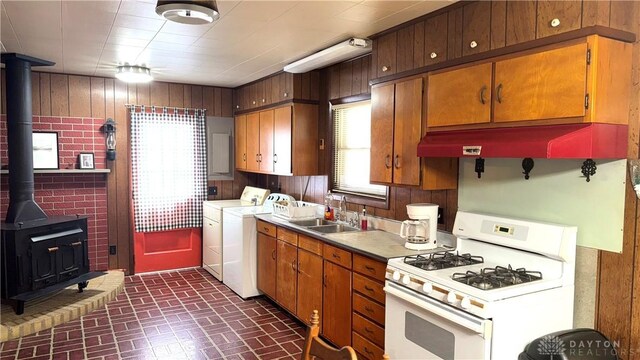 120 W Doris Dr, Fairborn, OH 45324 - kitchen featuring white gas range oven, washer and clothes dryer, a wood stove, brick patterned flooring, and healthy amount of natural light