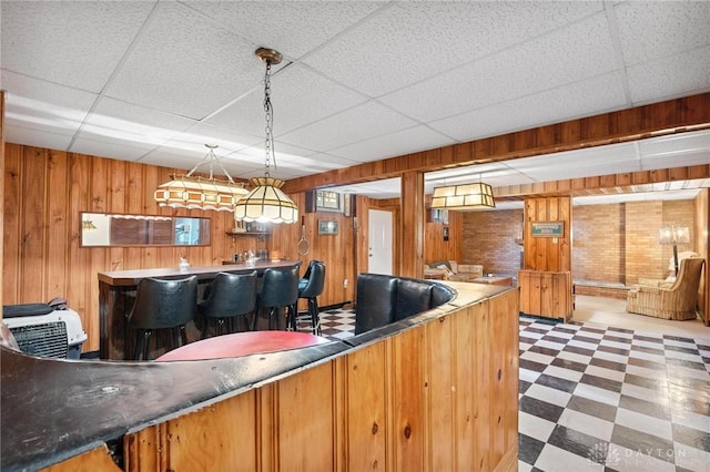1009 Cottage Court Dr, Fairborn, OH 45324 - kitchen featuring tile patterned floors, a paneled ceiling, wooden walls, and brown cabinetry