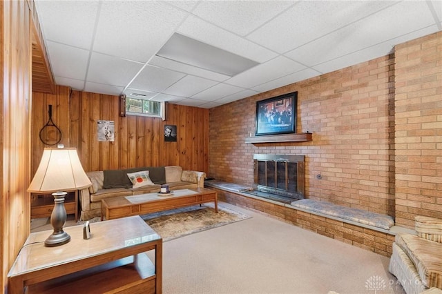 1009 Cottage Court Dr, Fairborn, OH 45324 - carpeted living room featuring a drop ceiling, wood walls, and a fireplace