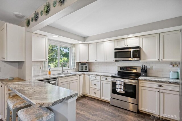 1009 Cottage Court Dr, Fairborn, OH 45324 - kitchen featuring stainless steel appliances, a peninsula, backsplash, dark wood finished floors, and a breakfast bar area