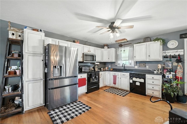 204 Ivy Creek Cv, Jamestown Vlg, OH 45335 - kitchen with black appliances, dark countertops, ceiling fan, light wood-style floors, and white cabinetry
