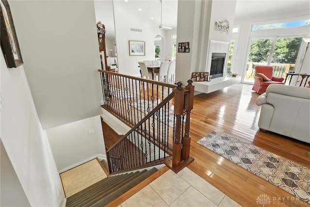 6885 Willow Creek Run, Liberty Twp, OH 45044 - staircase with a towering ceiling, ceiling fan, a tiled fireplace, and wood finished floors