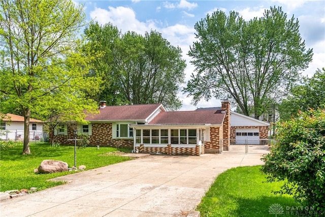2841 Prospect Dr, Fairborn, OH 45324 - view of front of property with a chimney, concrete driveway, a garage, and a sunroom
