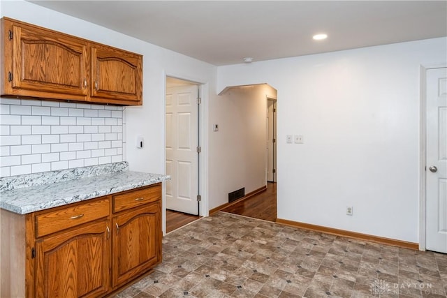 2841 Prospect Dr, Fairborn, OH 45324 - kitchen featuring arched walkways, brown cabinets, tasteful backsplash, light stone counters, and recessed lighting