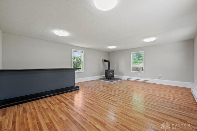 9351 Marcella Dr, Franklin, OH 45005 - workout area with a wood stove, a baseboard heating unit, light wood-style floors, healthy amount of natural light, and a textured ceiling