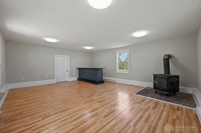 9351 Marcella Dr, Franklin, OH 45005 - unfurnished living room with a baseboard radiator, light wood-type flooring, a wood stove, and a baseboard heating unit