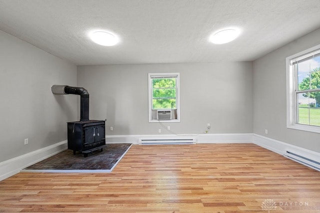 9351 Marcella Dr, Franklin, OH 45005 - unfurnished living room featuring wood finished floors, a baseboard heating unit, a wood stove, plenty of natural light, and a textured ceiling