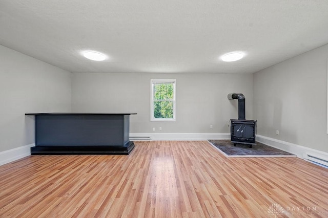 9351 Marcella Dr, Franklin, OH 45005 - unfurnished living room with a wood stove, wood finished floors, and a baseboard heating unit