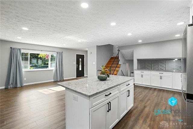 1937 Wilene Dr, Beavercreek, OH 45432 - kitchen with a center island, dark wood-style flooring, a textured ceiling, white cabinets, and light stone countertops