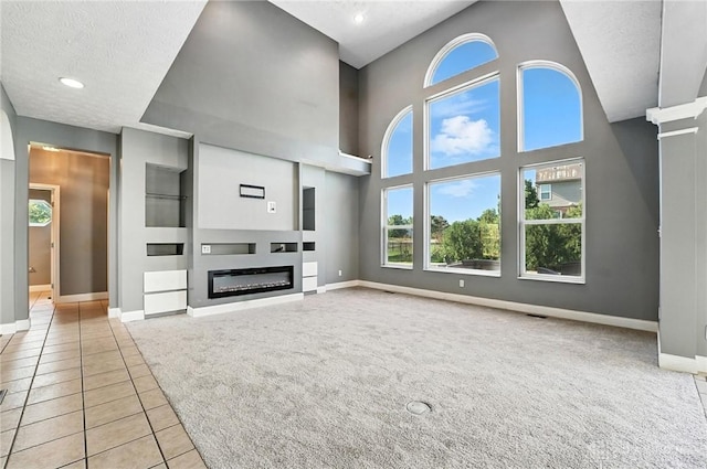 4300 Turtledove Way, Miamisburg, OH 45342 - unfurnished living room with light carpet, a glass covered fireplace, light tile patterned floors, built in features, and a towering ceiling