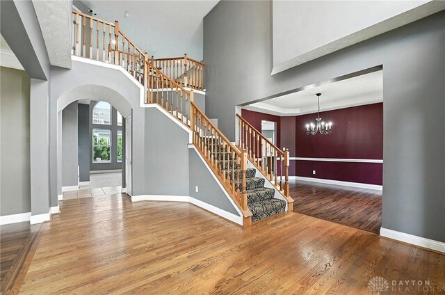 4300 Turtledove Way, Miamisburg, OH 45342 - stairs featuring arched walkways, wood finished floors, a chandelier, and a high ceiling