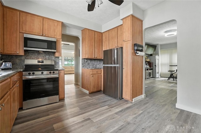 1551 W Main St, New Lebanon, OH 45345 - kitchen with appliances with stainless steel finishes, ceiling fan, light wood-type flooring, tasteful backsplash, and brown cabinets