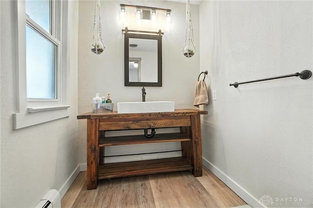 1551 W Main St, New Lebanon, OH 45345 - bathroom featuring wood finished floors, vanity, and a baseboard heating unit