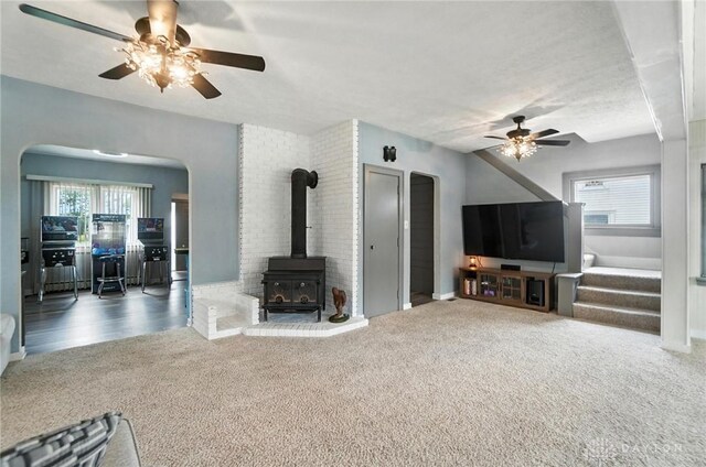 1551 W Main St, New Lebanon, OH 45345 - carpeted living room featuring ceiling fan, arched walkways, a wood stove, and plenty of natural light