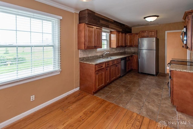 557 W N Bend Rd, Springfield Twp, OH 45224 - kitchen with appliances with stainless steel finishes, brown cabinetry, tasteful backsplash, light stone counters, and crown molding