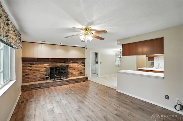 2184 Broadbent Way, Dayton, OH 45440 - unfurnished living room featuring ceiling fan, wood finished floors, washer and dryer, and a fireplace