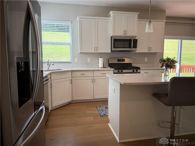 11916 Abbeytown Dr, Colerain Twp, OH 45251 - kitchen featuring appliances with stainless steel finishes, light wood-style floors, white cabinets, a breakfast bar, and decorative light fixtures
