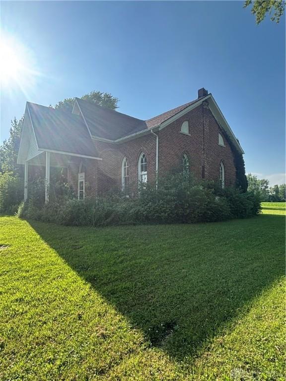 6008 Delisle-Fourman Rd, Arcanum, OH 45304 - view of front facade featuring a chimney, a front lawn, and brick siding
