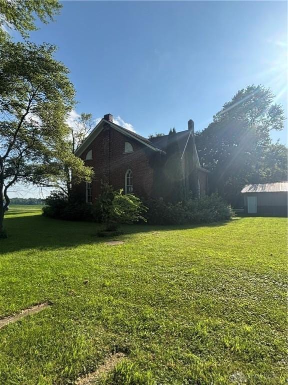 6008 Delisle-Fourman Rd, Arcanum, OH 45304 - view of side of home with a lawn, a chimney, and brick siding