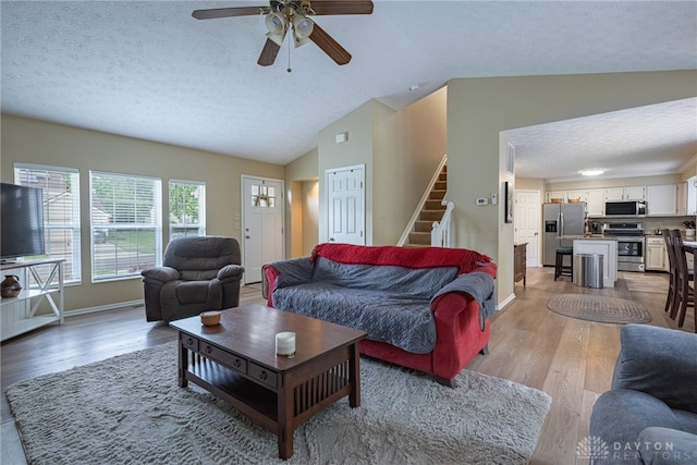947 Stone Ridge Ln, Lebanon, OH 45036 - living room featuring a textured ceiling, lofted ceiling, light wood-style floors, stairs, and ceiling fan