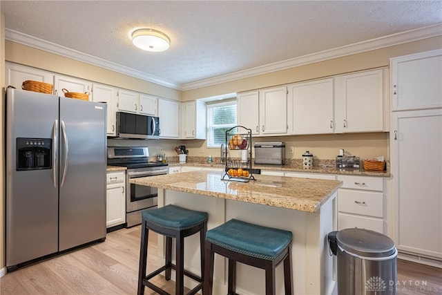 947 Stone Ridge Ln, Lebanon, OH 45036 - kitchen with stainless steel appliances, light wood-style flooring, a kitchen breakfast bar, crown molding, and white cabinetry