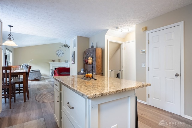 947 Stone Ridge Ln, Lebanon, OH 45036 - kitchen with a textured ceiling, white cabinetry, light wood finished floors, a kitchen island, and pendant lighting